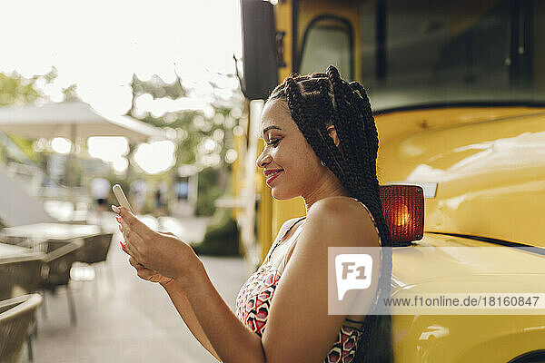 Lächelnde junge Frau  die ihr Smartphone benutzt