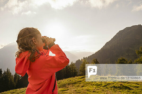 Girl wearing red jacket looking through binoculars