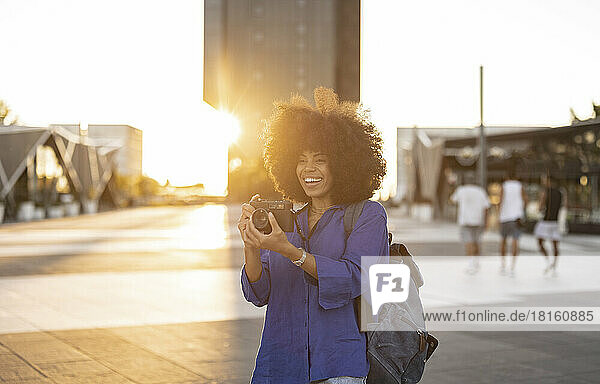Happy woman with Afro hairstyle photographing through camera