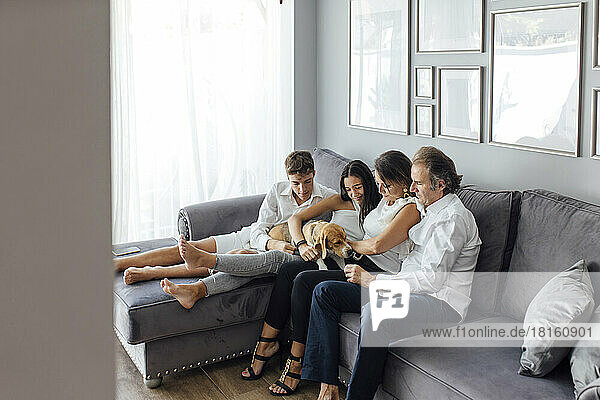Familie mit Hund auf Sofa im Wohnzimmer zu Hause