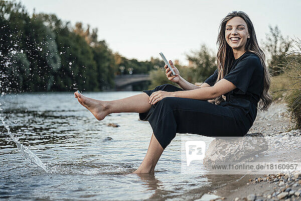 Cheerful woman splashing water with leg