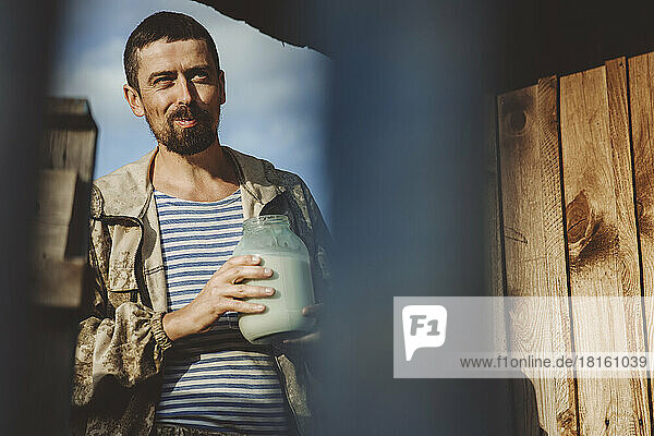 Reifer Mann mit einem Glas frischer Milch an einem sonnigen Tag