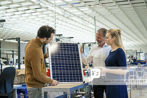 Businesswoman with colleagues examining solar panel at industry