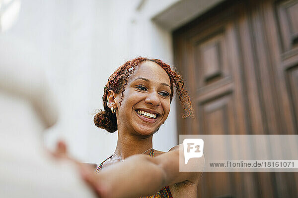 Happy woman with curly hair in front of door