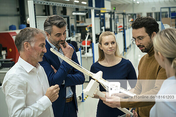 Businessman examining wind turbine model and discussing with colleagues in industry