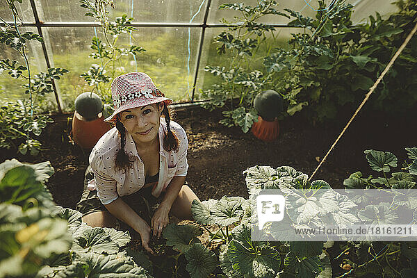 Smiling farmer wearing hat in greenhouse