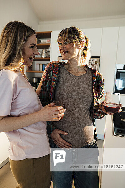 Smiling expectant woman talking to sister at home