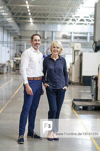 Happy senior businesswoman standing by colleague in industry