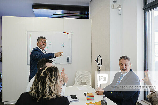 Mature businessman discussing strategy with colleagues in meeting at office
