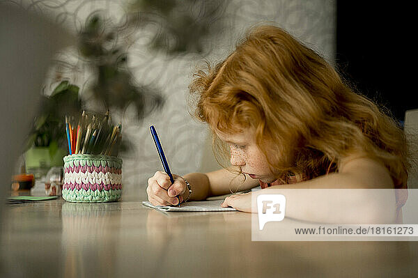 Mädchen zeichnet mit Farbstift am Tisch