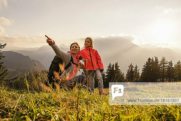 Smiling woman pointing by daughter standing on mountain