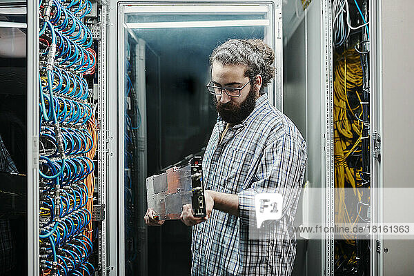 IT expert examining machine part in server room