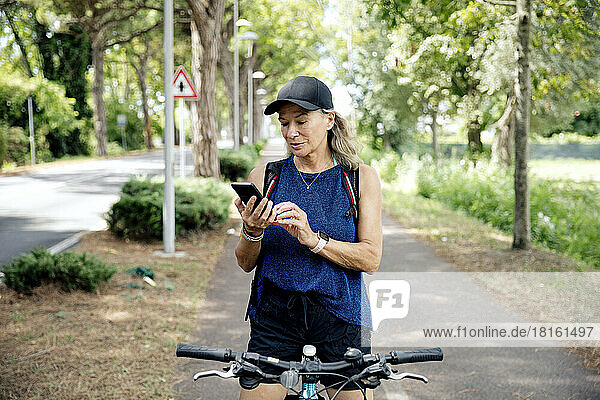Senior woman using smart phone on bicycle