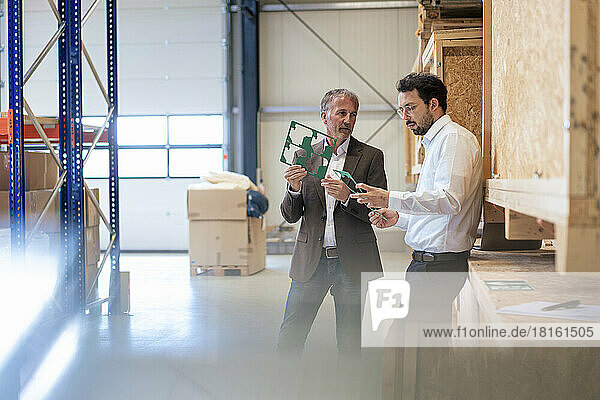 Businessmen examining mother board in warehouse