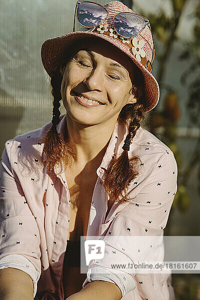 Smiling woman wearing hat sitting with eyes closed