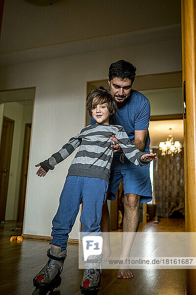 Father helping son skating at home