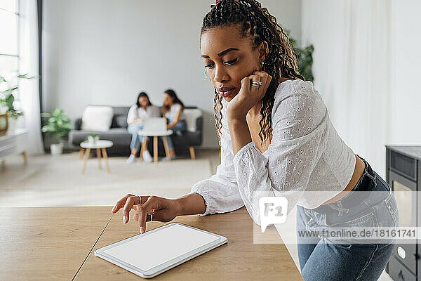 Junge Frau benutzt Tablet-PC am Tisch im Wohnzimmer