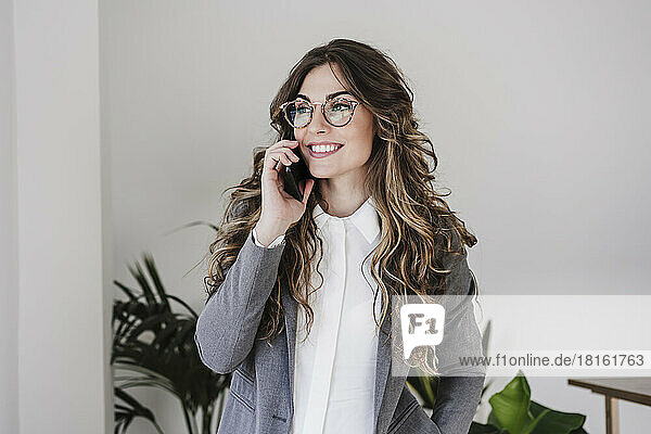 Lächelnde Geschäftsfrau benutzt Mobiltelefon im Büro