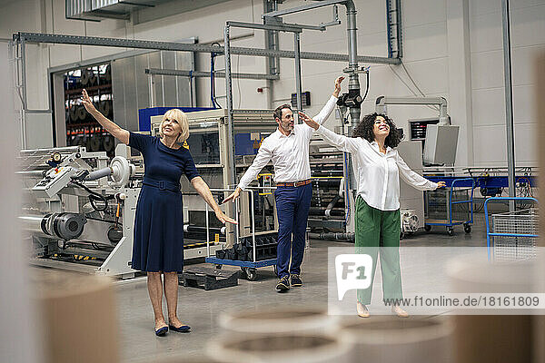 Happy business colleagues with arms outstretched in industry