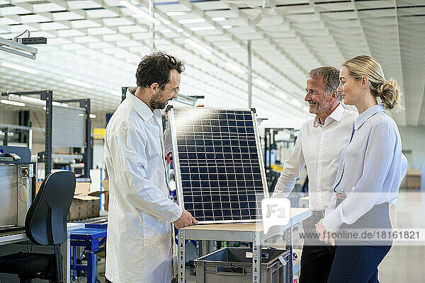 Engineer discussing over solar panel with colleague at industry