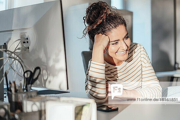 Happy businesswoman day dreaming at desk in office
