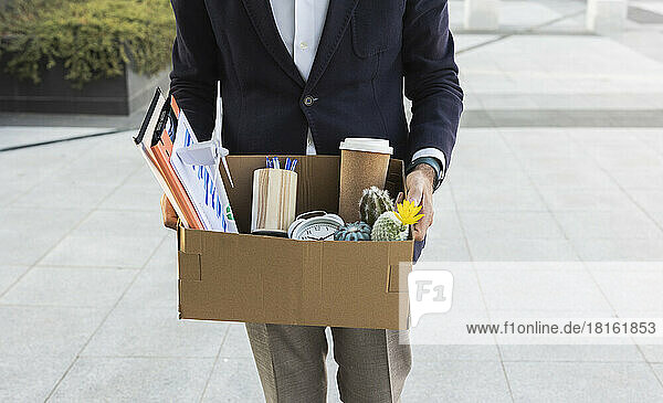 Geschäftsmann verlässt das Büro und hält einen Karton mit Büromaterial in der Hand