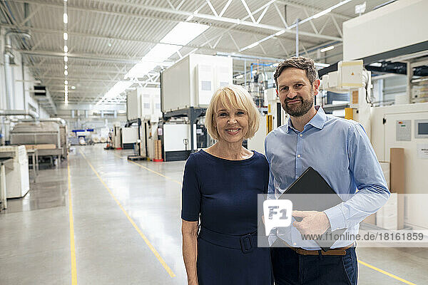 Happy senior businesswoman with colleague standing in industry