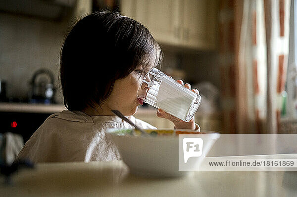 Junge trinkt zu Hause Milch aus Glas