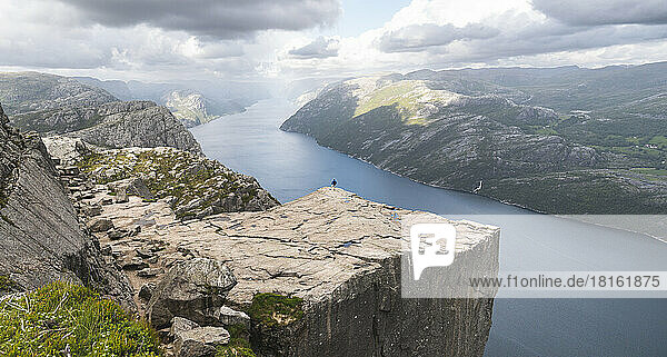 Famous Pulpit rock by Lysefjorden fjord with hiker standing at edge  Norway