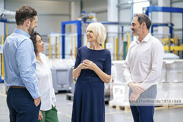 Happy senior businesswoman talking with colleagues in industry