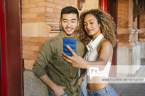 Smiling multiracial friends taking selfie on mobile phone