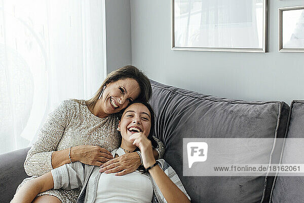 Mutter und Tochter lachen zu Hause auf dem Sofa im Wohnzimmer