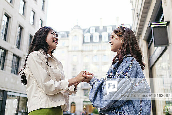 Young lesbian couple holding hands standing in city