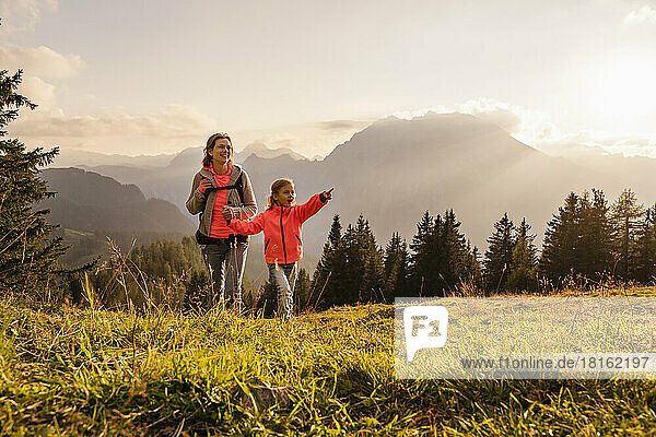 Smiling woman holding daughter's hand hiking on mountain