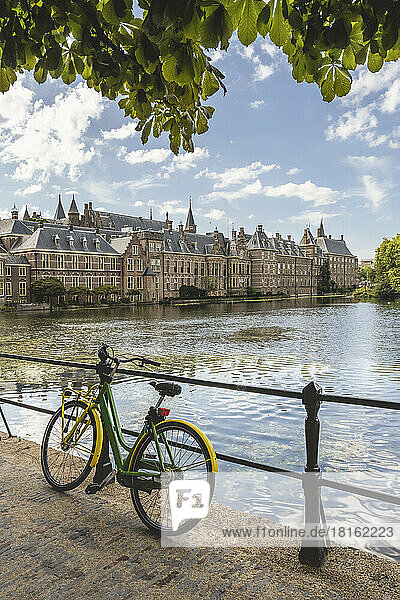 Netherlands  South Holland  The Hague  Bicycle leaning on railing of bridge stretching over Hofvijver lake canal with Binnenhof government office in background