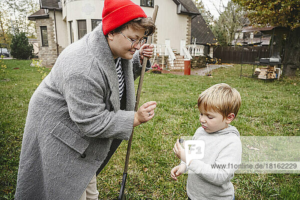 Mother giving blackberry to son standing in back yard