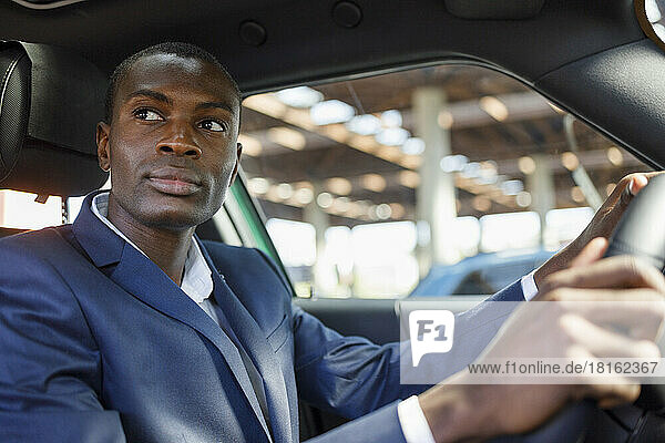 Thoughtful young businessman driving car