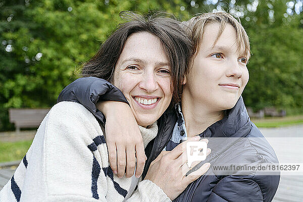 Son arm around of mother in park