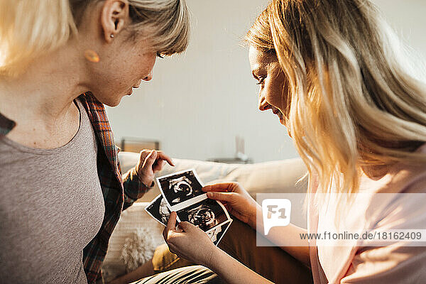 Frau diskutiert zu Hause über Ultraschall mit schwangerer Schwester