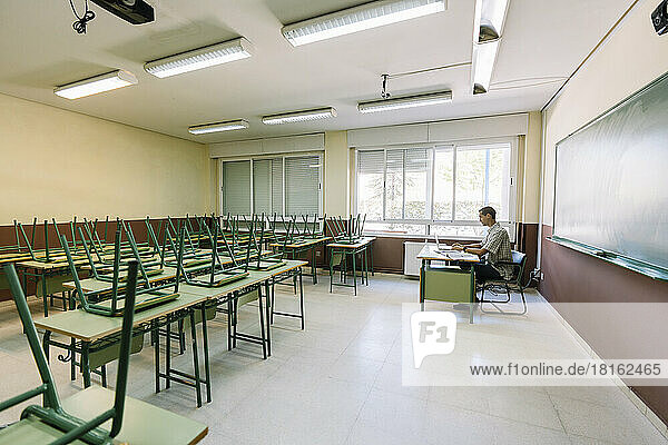 Math teacher sitting in empty classroom