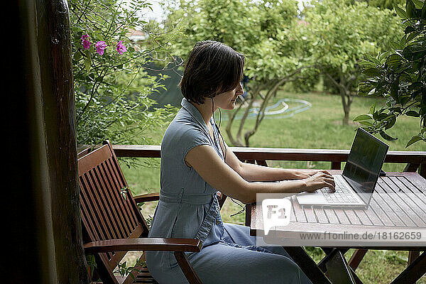 Freelancer working on laptop sitting on balcony
