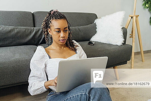 Engagierter junger Freiberufler nutzt Laptop im Wohnzimmer