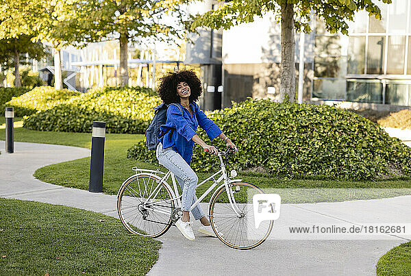 Smiling Afro woman with bicycle on footpath at park