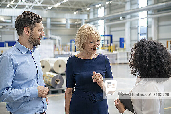 Smiling senior businesswoman discussing with colleagues in industry