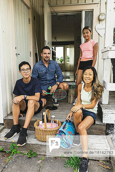 Multiracial family with picnic supplies at porch