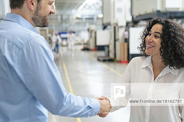 Smiling businesswoman shaking hand with businessman