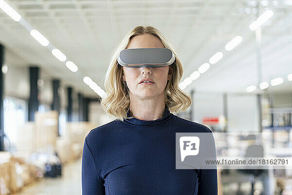 Blond businesswoman wearing virtual reality simulator at industry