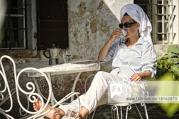 Frau mit Handtuch trinkt morgens Kaffee auf dem Dach