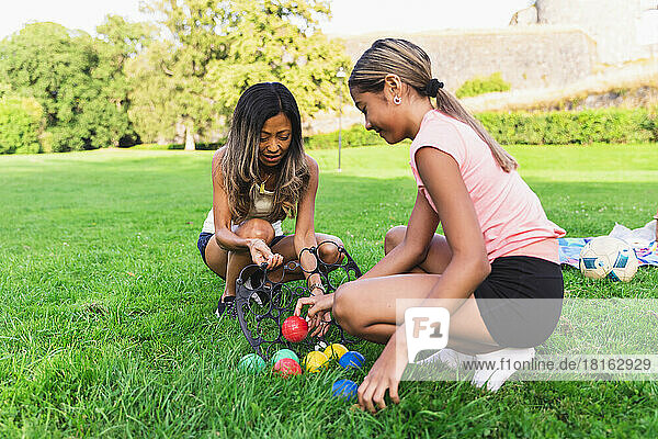 Mother and daughter playing boules crouching on grass