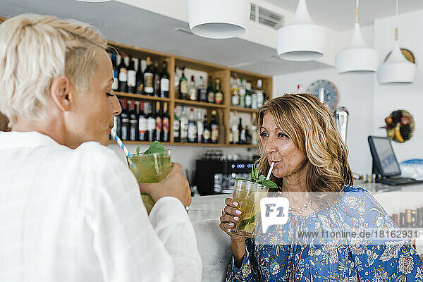 Mature businesswoman with friend enjoying cocktail drinks at bar